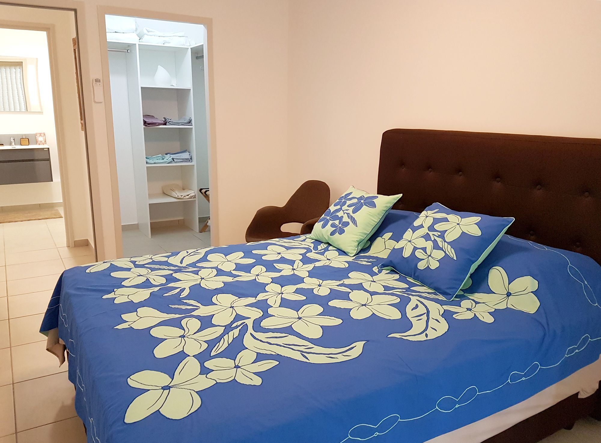 A bedroom with a bed, a brown upholstered headboard, and a wardrobe with shelves.