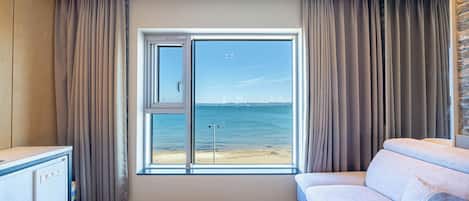 Una habitación moderna con un amplio ventanal que ofrece vistas al mar y barcos a lo lejos.
