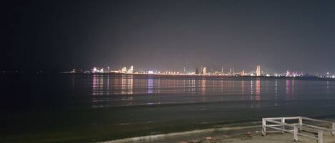 Een nachtzicht van een waterkant met verlichte gebouwen en een brug.