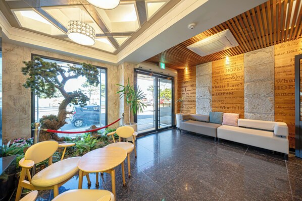 A reception area with a wooden ceiling, a large tree, and a sofa with cushions. - Pohang Yeongildae Hotel View (Pohang)