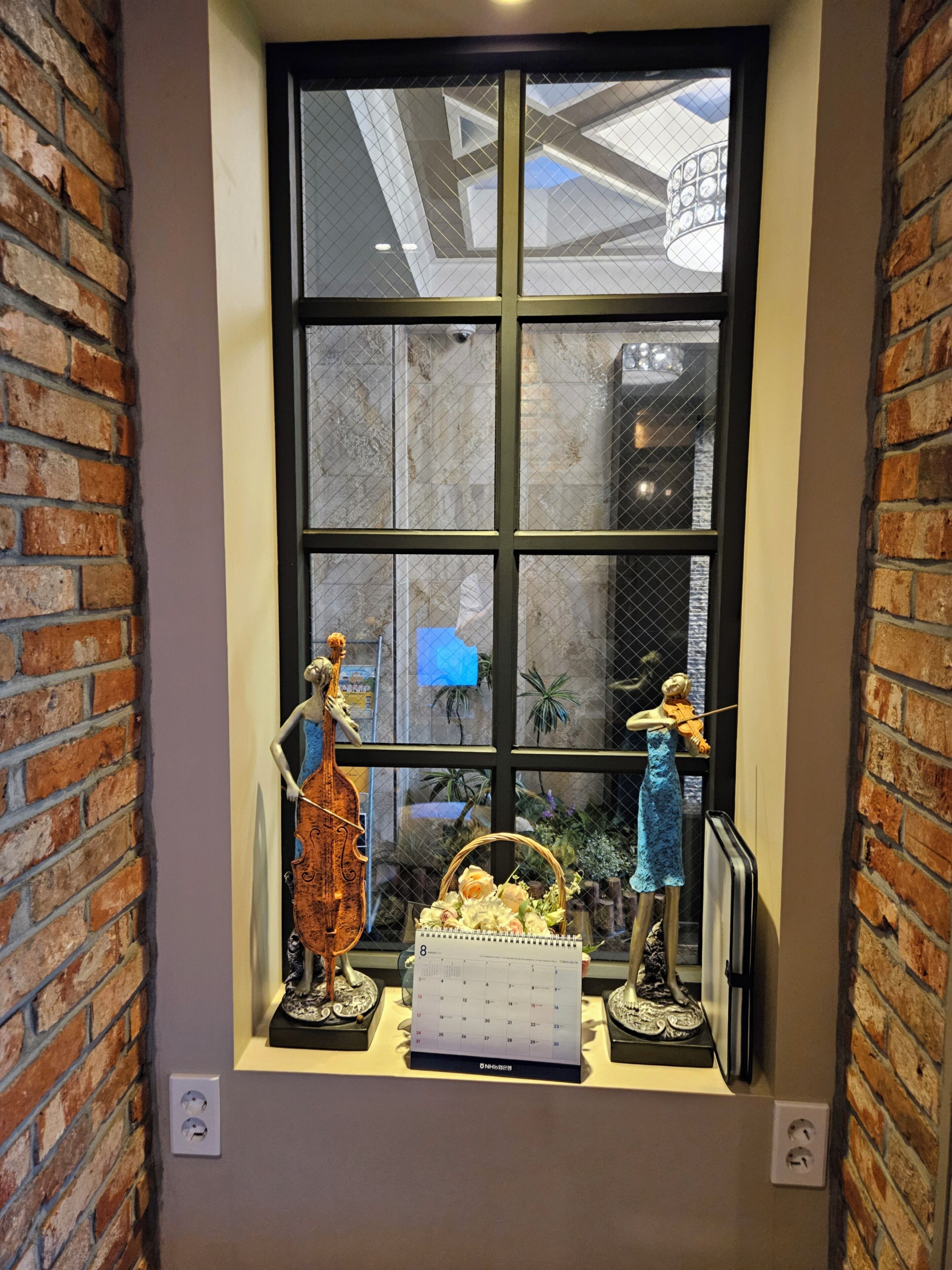 A window with a view of a brick wall and a ceiling with a geometric design.