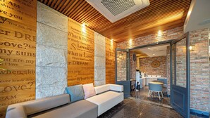 A modern lobby with a white sofa, a brick wall, and a wooden ceiling. - Pohang Yeongildae Hotel View (Pohang)