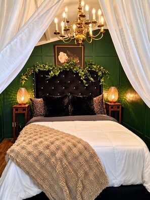Une chambre à coucher avec une tête de lit capitonnée, un lustre et deux lampes de chevet.