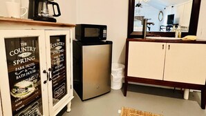 A compact kitchen with a coffee maker, microwave, and a small refrigerator. There is a cabinet with a sign advertising local attractions. A large mirror reflects part of the room. - CUTE CABIN, PRIVATE HOT TUB, QUEEN BED, SMALL TOWN, 4 MILES TO RATCLIFF LAKE (Kennard)