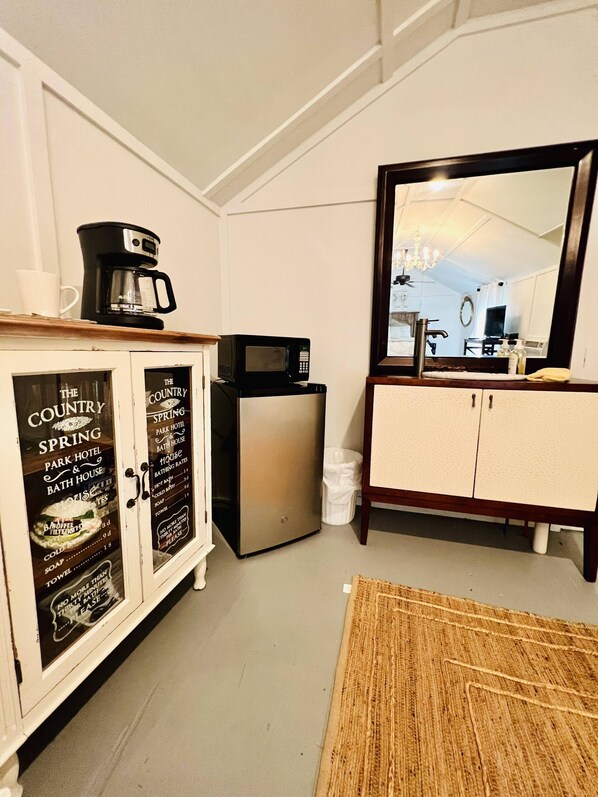 A compact kitchen with a coffee maker, microwave, and a small refrigerator. There is a cabinet with a sign advertising local attractions. A large mirror reflects part of the room. - CUTE CABIN, PRIVATE HOT TUB, QUEEN BED, SMALL TOWN, 4 MILES TO RATCLIFF LAKE (Kennard)