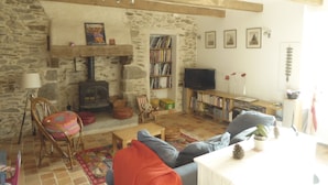 Uma sala de estar aconchegante com parede de pedra, lareira, estante de livros e televisão.