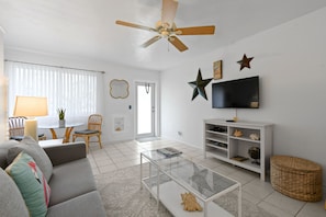 A living room with a sofa, coffee table, TV, and decorative items. - one bedroom furnished apartment by beach (West Palm Beach)