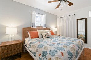 A bedroom with a bed, nightstands, a ceiling fan, and a large mirror. - one bedroom furnished apartment by beach (West Palm Beach)