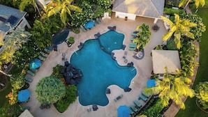 Vista aérea de un resort con varias piscinas, zonas de descanso y palmeras.