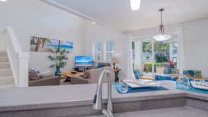 Una sala de estar moderna con sofá, televisor y comedor.