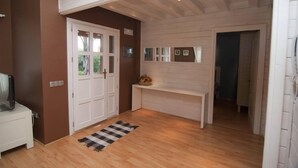 A hallway with a wooden floor, white walls, and a white bench.