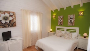 A bedroom with a bed, a TV on a cabinet, and artwork on the walls.