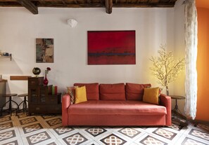 A living room with a red sofa, patterned floor, and a red abstract painting on the wall.