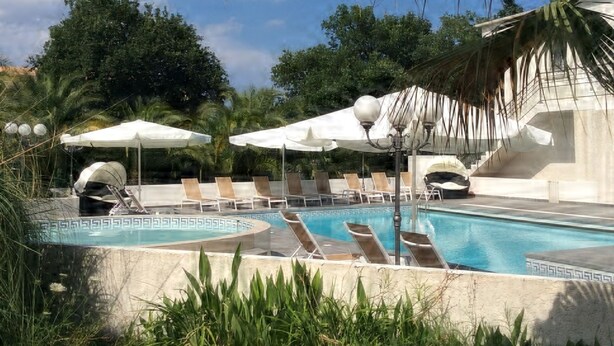 A pool area with lounge chairs and umbrellas, surrounded by palm trees and greenery. - Villa Cigale 3 - 8 people 300m from the beach with shared pool (San-Nicolao)