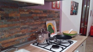 A kitchen with a gas stove, a sink, and a brick-patterned backsplash. - CASE COLOMBO AND MATTARELLA central apartment with wi-fi and free parking space (San Vito Lo Capo)