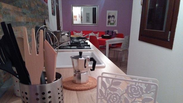 A kitchen with a gas stove, a coffee maker, and a metal utensil holder. - CASE COLOMBO AND MATTARELLA central apartment with wi-fi and free parking space (San Vito Lo Capo)