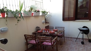 A patio with a table set for four, surrounded by wooden chairs with patterned cushions. - CASE COLOMBO AND MATTARELLA central apartment with wi-fi and free parking space (San Vito Lo Capo)