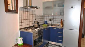 Une cuisine de taille réduite équipée d’une cuisinière à gaz, d’un four et d’un réfrigérateur.