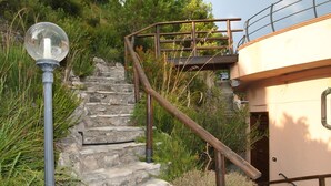 Una escalera de piedra que lleva a un edificio con barandilla metálica y un farol.