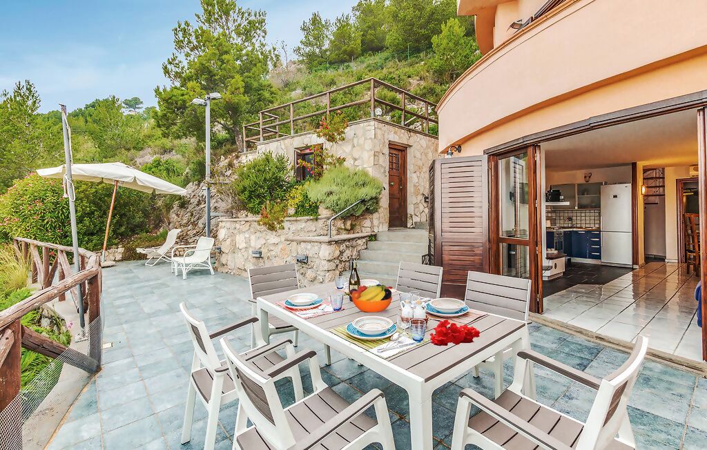 Eine Terrasse mit Esstisch und Stühlen, mit Blick auf ein Steinhaus mit Balkon.