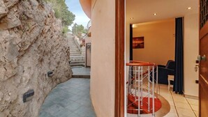 Entrada de hotel con pared de piedra, una escalera que conduce al piso superior y una zona de estar con una pared de acento roja.