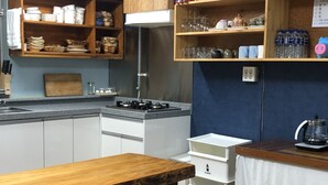 Una cocina compacta con armarios de madera, una estufa a gas y un comedor con una mesa y bancos de madera.