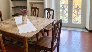 Een eethoek met een houten tafel, stoelen, een bloemenvaas en een kroonluchter.