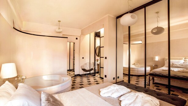 Ein Hotelzimmer mit einem großen Bett, einem separaten Badezimmer, einer Sitzecke und einer Rezeption.