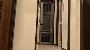 A hallway with a wooden floor, white walls, and a door at the end. - House Kira (Chatan)