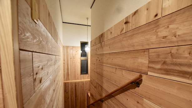 A narrow wooden hallway with a wooden handrail and a window at the end. - House Kira (Chatan)