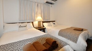 A hotel room with two beds, a nightstand with a lamp, and an air conditioning unit on the wall. - House Kira (Chatan)