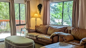 A living room with a brown leather sofa, a matching ottoman, and a floor lamp.