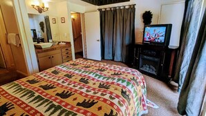 A bedroom with a large bed, a television, a dresser, and a staircase leading to an upper level.