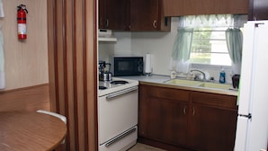 Une cuisine de taille réduite, équipée d’une cuisinière, d’un four à micro-ondes, d’un évier et de placards.