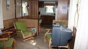 Un espace de vie compact comprenant un coin cuisine, un coin repas avec des meubles en bois et un téléviseur.