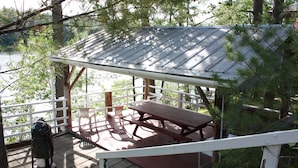 Un espace extérieur abrité, doté de tables de pique-nique et d’un banc, le tout entouré d’arbres.