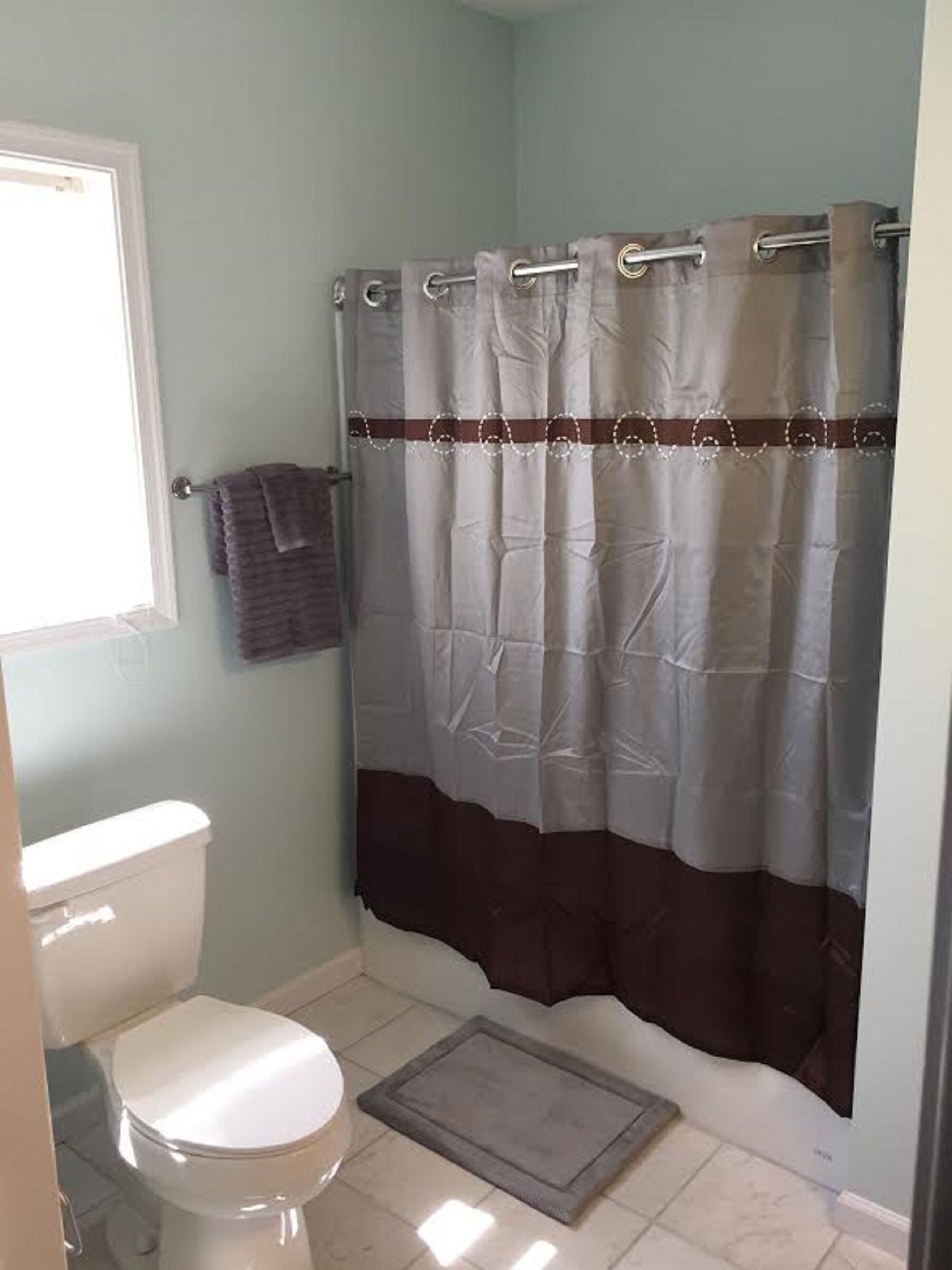 A bathroom with a white toilet, a shower curtain, and a towel rack.