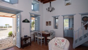 A spacious living area with a dining table, chairs, a sofa, and a staircase leading to an upper level. - Chora villa 1 with unique sea view (Hora)
