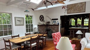 A dining area with a wooden table and chairs, a red patterned armchair, and a lamp on a side table. - Bright and cozy menemsha cottage (Chilmark)