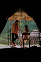 Una pareja en una habitación con techo de paja y vistas a exuberante vegetación.
