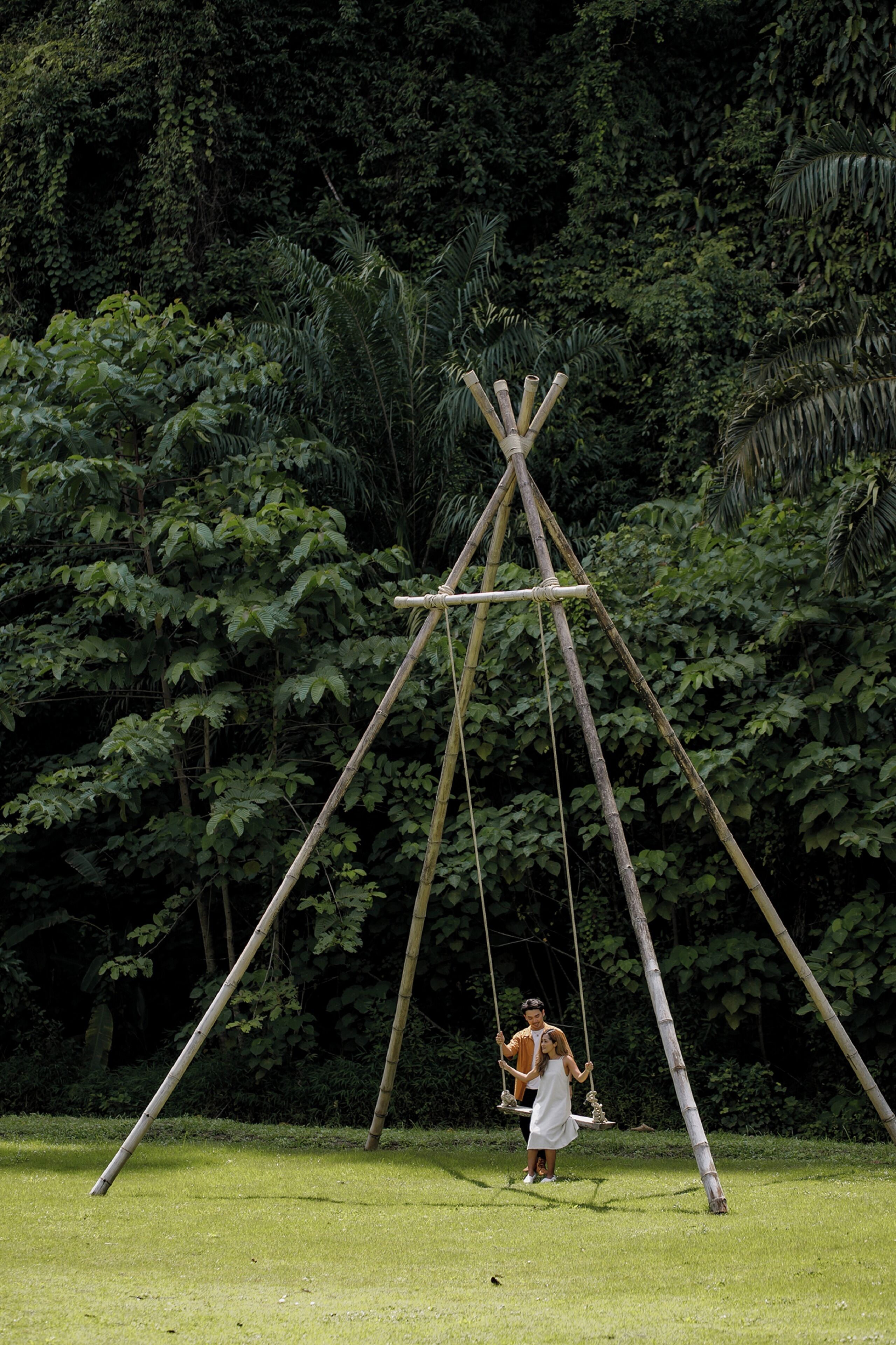 A bamboo swing set in a lush green park.