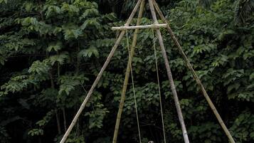 A bamboo swing set in a lush green park.