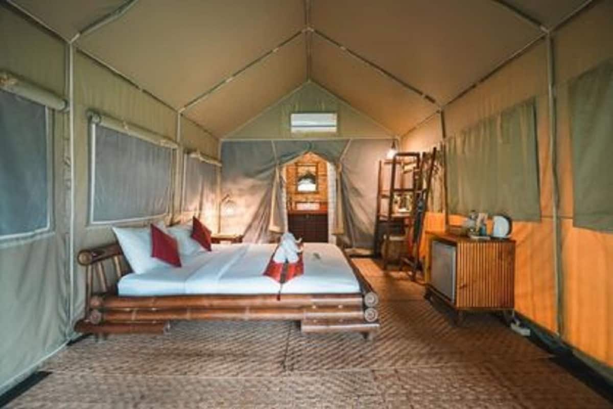 A tented room with a bed, a desk, and a wardrobe.