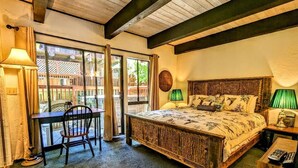 Ein Schlafzimmer mit einem großen Bett, einem Schreibtisch und einem Stuhl. Ein Fenster bietet Blick auf Gebäude.