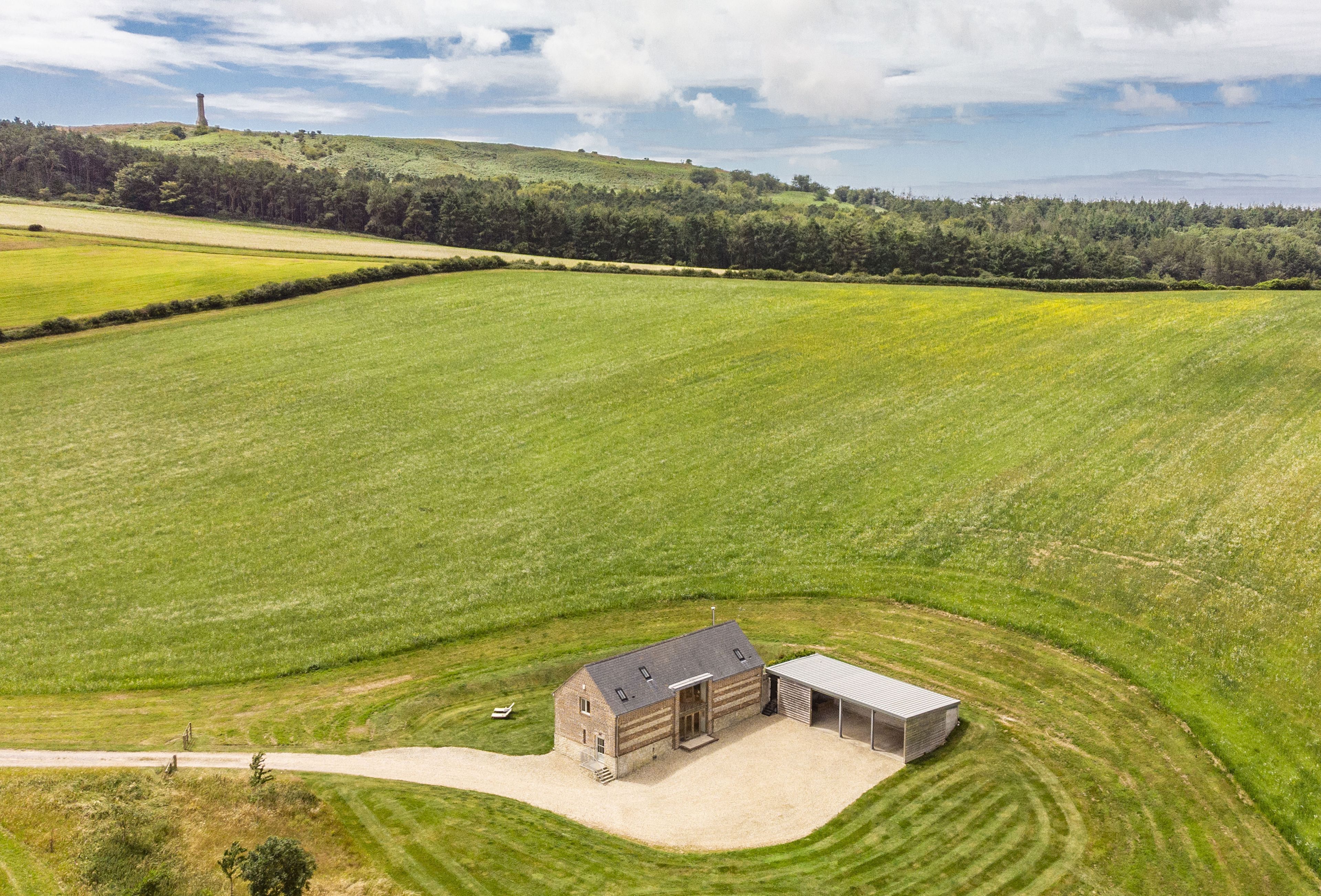 A large, open field with a farmhouse and a barn.