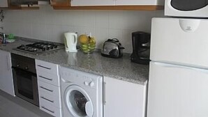 A compact kitchen with a gas stove, a washing machine, a coffee maker, and a microwave. - 1 Bedroom Apartment Can Sleep 4 People With Private Pool And Air Conditioning (Armação de Pêra)