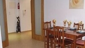 A dining area with a wooden table and chairs, a glass-top coffee table, and a painting on the wall. - 1 Bedroom Apartment Can Sleep 4 People With Private Pool And Air Conditioning (Armação de Pêra)