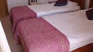Two single beds with pink and white bedding, a wooden headboard, a chair, and a bedside table with a lamp. - 1 Bedroom Apartment Can Sleep 4 People With Private Pool And Air Conditioning (Armação de Pêra)