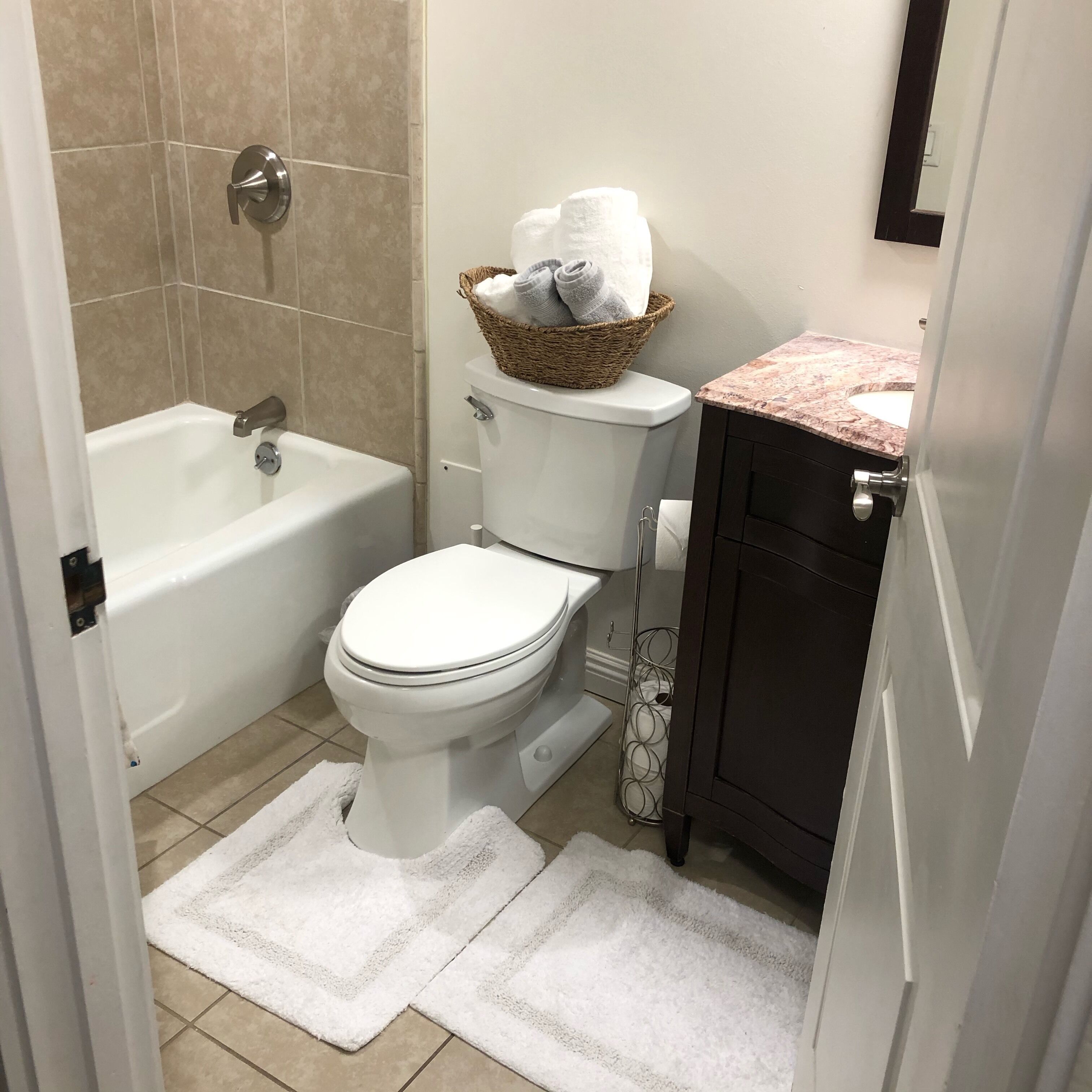 A bathroom with a white toilet, a bathtub, and a sink with a marble countertop.