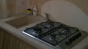 A kitchen with a gas stove, a sink, and cabinets. - Palazzolo Acreide Charming cottage for two people !!  (Palazzolo Acreide)